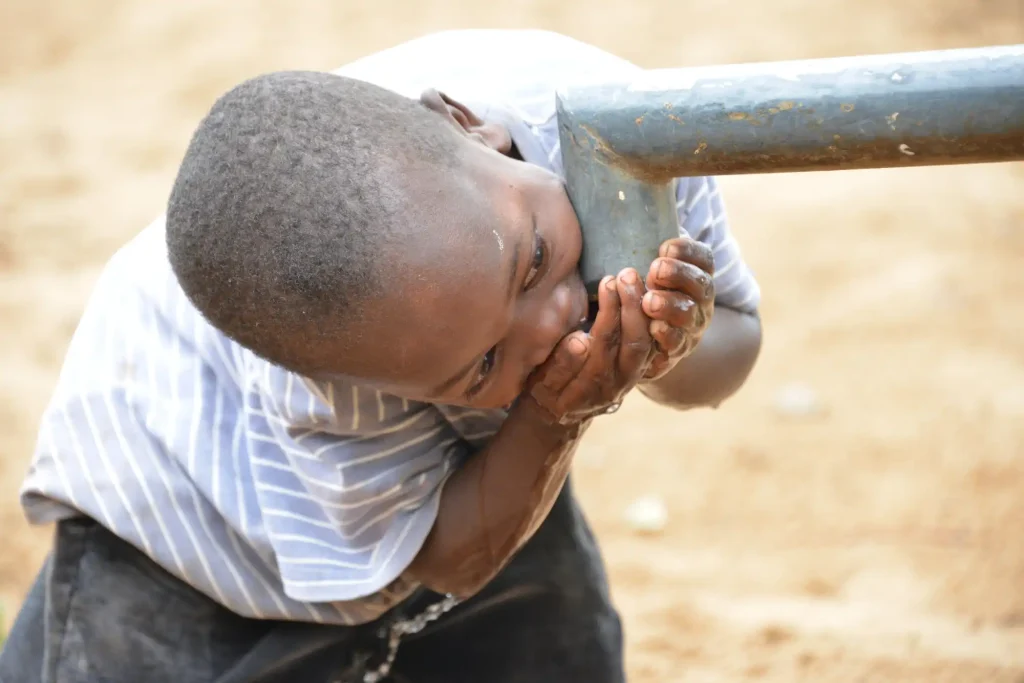 Boy drinking from the pump in his village